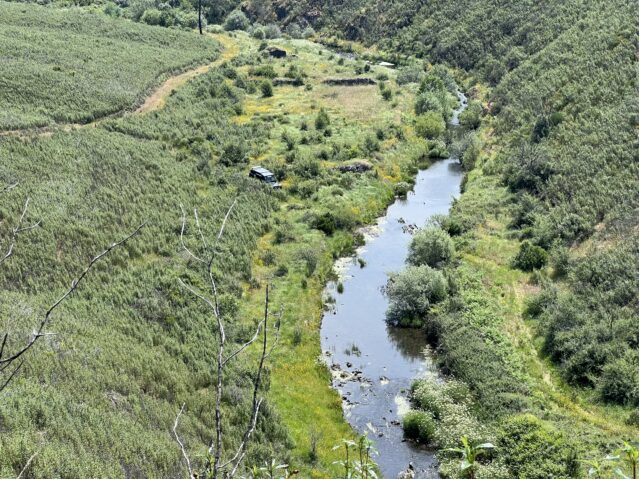 Landrover driving through forested river valley in Portugal